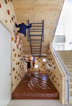 two people climbing up the side of a wall with plastic tarps on it and some stairs