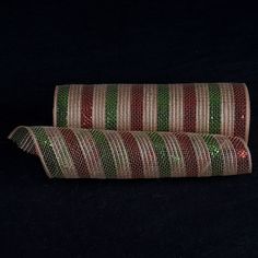 two rolls of red, green and white striped ribbon on black background with space for text