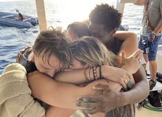 three people hugging each other on a boat