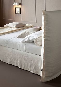 a bed with white linens and pillows on it's headboard in a bedroom