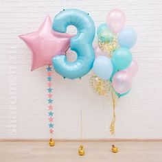 balloons and streamers in the shape of numbers are arranged against a white brick wall