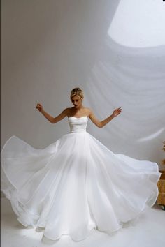 a woman in a white dress is posing for the camera with her arms spread out