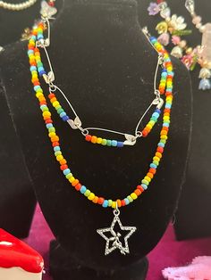 multicolored beaded necklace with star pendant on display in front of other beads