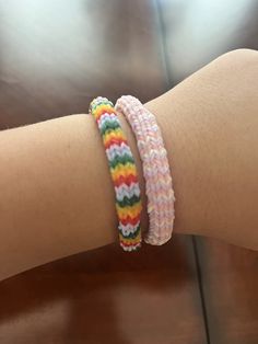 a woman's arm with two bracelets that have different colors and designs on it