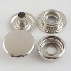 three metal knobs and two silver plates on a white surface