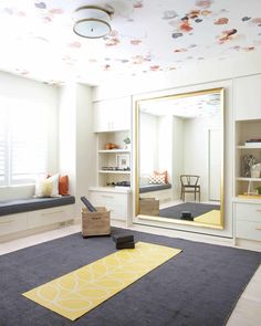 a room with a large mirror and various decorations on the ceiling, along with an area rug for yoga mats