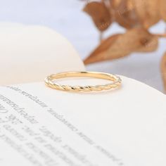 a gold ring sitting on top of an open book next to a leafy plant