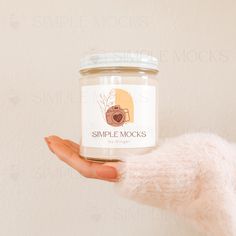 a person holding a jar of simple mocks in their left hand with a white background