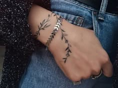 a woman's arm with an arrow tattoo on it and a chain attached to the wrist