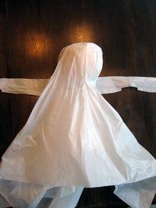 a paper doll is standing on a wooden floor and wearing a white dress with long sleeves