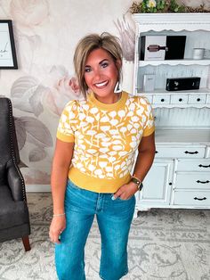 This short-sleeve knit top is about to become your new go-to for effortless style. In a rich mustard hue, it's a vibrant pop of color that brightens up your wardrobe. A button keyhole in back adds a flirty, feminine touch to this lightweight sweater. Made from a cozy blend, it's the perfect transitional piece for fall weather. Pair it with distressed jeans and booties for a casual coffee date or style it with a midi skirt and heels for a night out. However you wear it, this versatile staple is s Short Sleeve Knit Top For Fall Day Out, Fall Short Sleeve Knit Top For Day Out, Short Sleeve Knit Top For Day Out, Fitted Mustard Top For Work, Mustard Fitted Tops For Work, Stretch Yellow Knit Top, Mustard Short Sleeve Tops For Fall, Yellow Stretch Short Sleeve Top, Yellow Fitted Knit Top For Fall