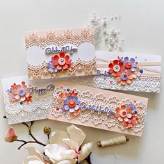 three handmade cards with flowers on them sitting next to some thread and bead