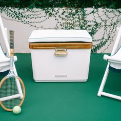 two tennis rackets and a cooler on a green surface