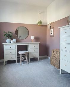 a white dresser sitting next to a mirror on top of a wooden cabinet in a bedroom