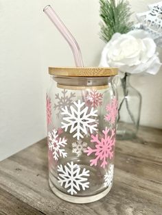 a glass jar with pink and white snowflakes painted on the side, holding a straw