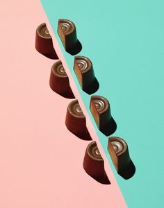 four pieces of chocolate cake sitting on top of each other in front of a blue and pink background