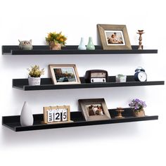 two black shelves with pictures and other items on them, one shelf has an alarm clock