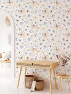 a room with a table and two stools in front of a flowered wall