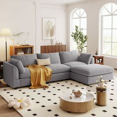 a living room with a large sectional couch and coffee table in the center, surrounded by windows