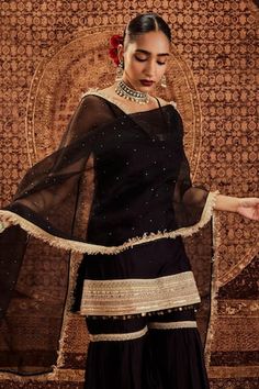 Black short strappy kurta with broad golden border embellishments and sequin tassels. Comes with lace trim sharara and organza dupatta with kiran lace edging.
Components: 3
Pattern: Embellished
Type Of Work: Lace, sequins, kiran lace
Neckline: Square
Sleeve Type: Sleeveless
Fabric: Kurta and Sharara: Pure Chanderi, Dupatta: Organza
Color: Black
Other Details: 
Attached lining
Length:
Kurta: 32 inches
Sharara: 42 inches
Model Height: 5ft 8inches, wearing size XS
Occasion: Sangeet - Aza Fashions Black Gharara, Strappy Kurta, Lace Kurta, Kurta And Sharara, Black Kurta, Chanderi Dupatta, Golden Border, Women Kurta, Straight Kurta