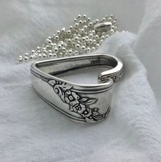 a close up of a silver ring on a white cloth with a beaded chain