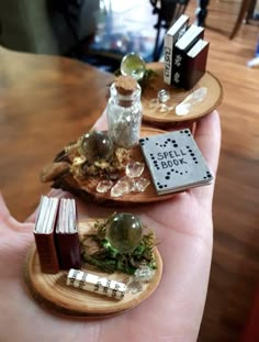 two small wooden trays with books and other items on them in someone's hand