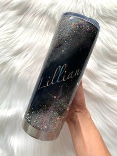 a hand holding a black and silver glittered personalized tumbler with the name lil ann on it