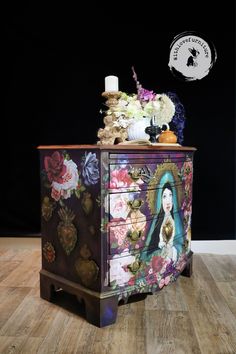 an ornate dresser with flowers on it and a candle sitting on top of the drawer