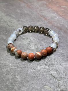 "Part of a new capsule collection of emotional support bracelets, featuring a carefully curated combination of the highest quality genuine stones, chosen to bring out the innate properties of each.  This is a limited time collection, so get yours while they last!   Available in the 2 sizes shown but if you need a different size please message me to confirm.   **Please remember that you need approximately .5\" - 1' above your wrist measurement for a comfortable fit; i.e. a 7\" bracelet will fit 6\" - 6.5\" wrists and an 8\" bracelet will fit 7\" - 7.5\" wrists.   This listing:   Poppy Jasper - said to be helpful in promoting contentment, tranquility, and nurturing Flower Agate - purported to be good for fostering harmony and bringing balance Smokey Quartz - excellent for bringing stability Spiritual Carnelian Bracelet With Natural Stones, Brown Gemstone Healing Bracelets, Brown Gemstone Bracelets For Healing, Holistic Agate Gemstone Bracelets, Everyday Spiritual Agate Bracelets, Spiritual Jasper Gemstone Beads Bracelets, Spiritual Jasper Bracelets With Gemstone Beads, Agate Healing Bracelet For Meditation, Healing Jasper Bracelets With Natural Stones