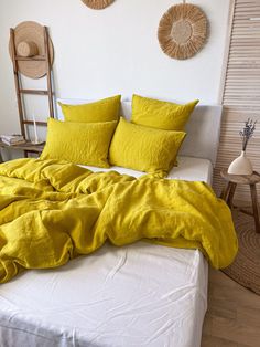 a bed with yellow sheets and pillows on it