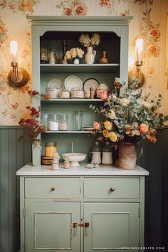 a green cabinet filled with dishes and flowers