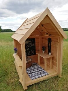 a small wooden shed with a chalkboard sign on the door and shelves in it