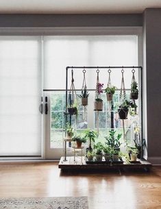 an indoor plant stand with potted plants hanging from it's sides in front of a sliding glass door