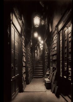 an old photo of a long narrow hallway with books on the walls and stairs leading up to them