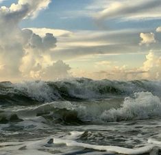 an ocean with waves crashing on the shore and clouds in the sky over it,