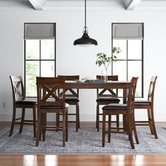 a dining room table with four chairs and a rug in front of the window,