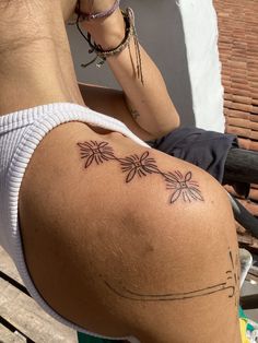 a woman sitting on top of a wooden bench next to a building with tattoos on her back