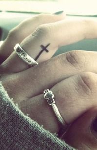 two people with rings on their fingers and one has a cross tattooed on the middle finger