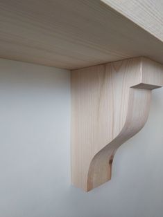 a wooden shelf with a curved corner on the wall next to a light colored wall