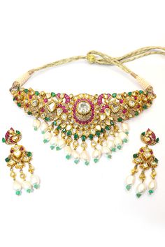 This Natural Ruby with Pearl and Emerald Necklace Set is a dazzling example of luxury and craftsmanship, meticulously designed to highlight the beauty of natural gemstones and the elegance of traditional jewelry. Crafted in 18k gold, this necklace is a masterpiece that showcases a harmonious blend of rubies, pearls, emeralds, and Polki diamonds. The necklace features vivid natural rubies, their deep red hue radiating passion and elegance. These rubies are perfectly complemented by the rich green of the emeralds, creating a striking contrast that is both eye-catching and sophisticated. Interspersed between the rubies and emeralds are lustrous pearls, adding a touch of softness and refinement to the piece. The pearls' subtle sheen enhances the necklace's overall elegance, balancing the bold Elegant Multi-stone Gold Jewelry Sets, Elegant Gold Multi-stone Jewelry Sets, Elegant Festive Multi-stone Jewelry Sets, Elegant Multi-stone Bridal Necklace For Festive Occasion, Elegant Multi-stone Bridal Necklace For Festivities, Elegant Festive Multi-stone Bridal Necklace, Elegant Multi-stone Kundan Necklace For Festive Occasions, Elegant Multi-stone Kundan Necklace For Wedding, Elegant Multi-stone Jewelry Sets As A Gift