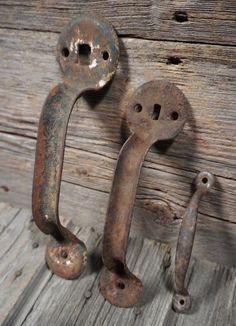 two old rusted metal door handles on a wooden wall next to a pair of nails