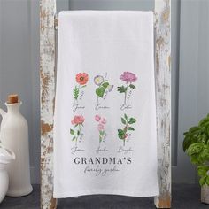 a white towel hanging on a wooden frame next to a potted plant and vase