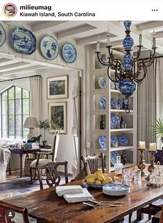 a dining room table with blue and white plates hanging from it's ceiling above it