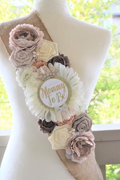 a white mannequin with flowers on it and a name tag that says mommy to be