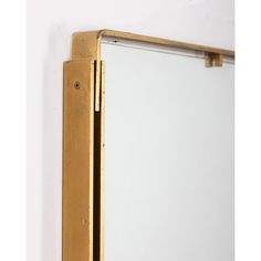 a mirror that is on the side of a wall next to a white wall with a gold frame