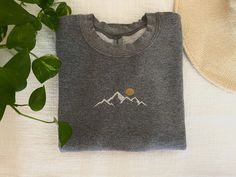 These unisex sweatshirts are the perfect way to get cozy and warm on a chilly day! Or to get as a gift for someone you love!  Made from 50% cotton and 50% polyester. This sweatshirt is super soft and comes in 3 sizes! - S - M - L and in 3 colors - Green - White - Gray A sweet mountain scene with a sun coming up behind it is embroidered on the front-center of the the sweatshirt.  When ordering choose the color and size of your sweatshirt and we will have it ready in 1-3 days!  When ordering stick Gray Winter Sweatshirt With Embroidered Text, Gray Embroidered Logo Sweatshirt For Winter, Cozy Winter Sweatshirt With Embroidered Logo, Winter Gray Sweatshirt With Embroidered Logo, Heather Grey Embroidered Logo Sweatshirt For Winter, Heather Grey Winter Sweatshirt With Embroidered Logo, Winter Heather Grey Sweatshirt With Embroidered Logo, Gray Mountain, Nature Embroidery