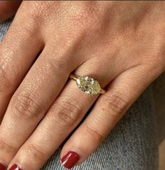 a woman's hand with red nails and a ring on her left hand, wearing a diamond engagement ring