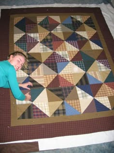 a woman laying on the ground next to a quilt