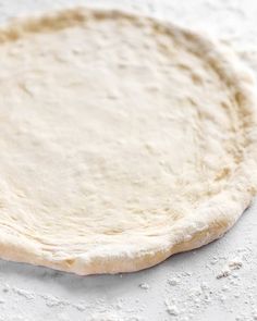 an uncooked pizza dough on a white surface