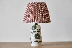 a lamp that is sitting on top of a wooden table in front of a white wall